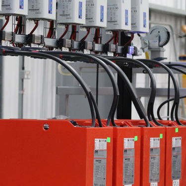 A row of lead acid batteries on charge in a warehouse