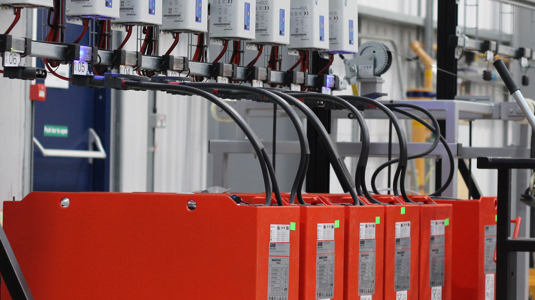 A row of lead acid batteries on charge in a warehouse
